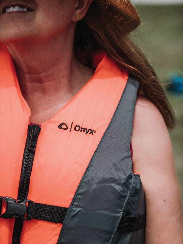 A woman wears an orange Onyx life jacket